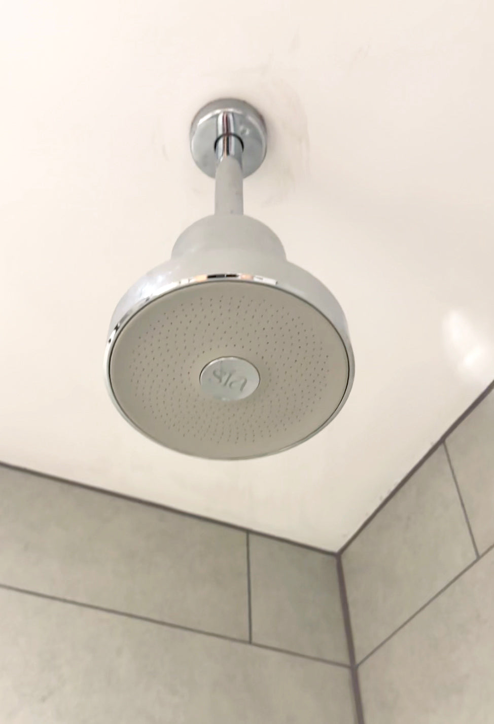 Shower head mounted on a ceiling in a bathroom setting