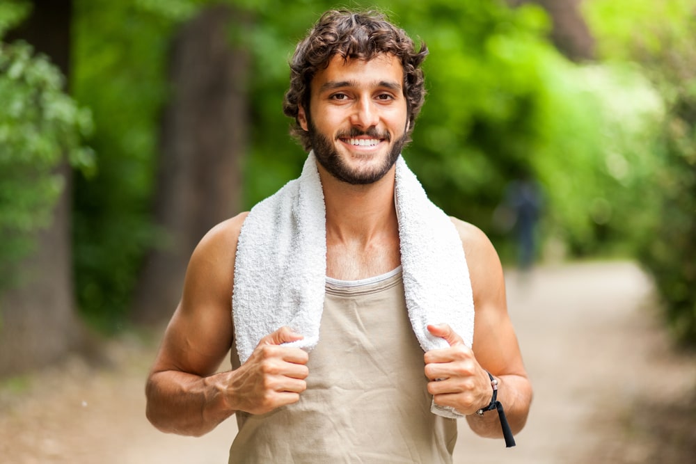 Young man training himself outdoor and smiling at camera
